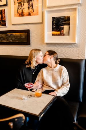 Couple sitting at restaurant table with drinks sharing romantic moment.