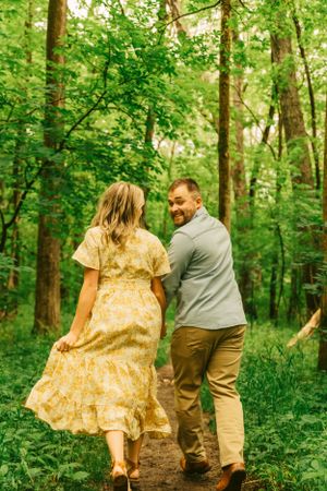 A couple strolling together on a winding path through vibrant spring woodland.