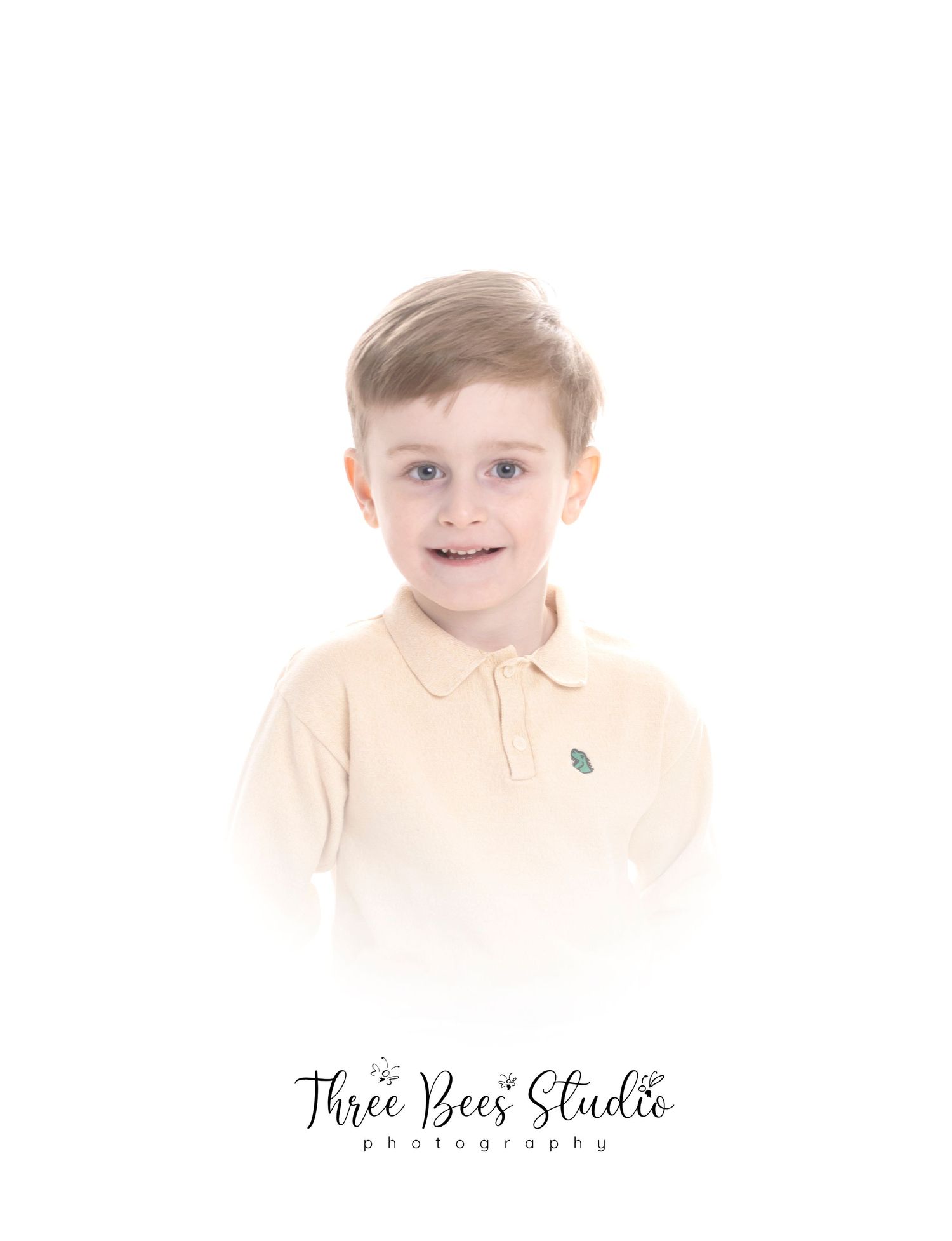 Soft focus portrait of child in light colored polo shirt against white background.