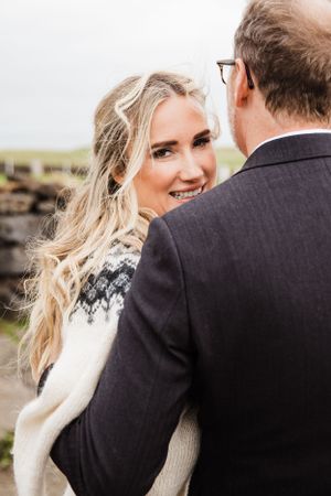 Intimate moment captured against a moody sky featuring a white knit wedding sweater.