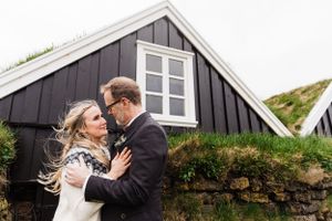 Romantic moment shared in front of a traditional black Nordic house with stone foundation.