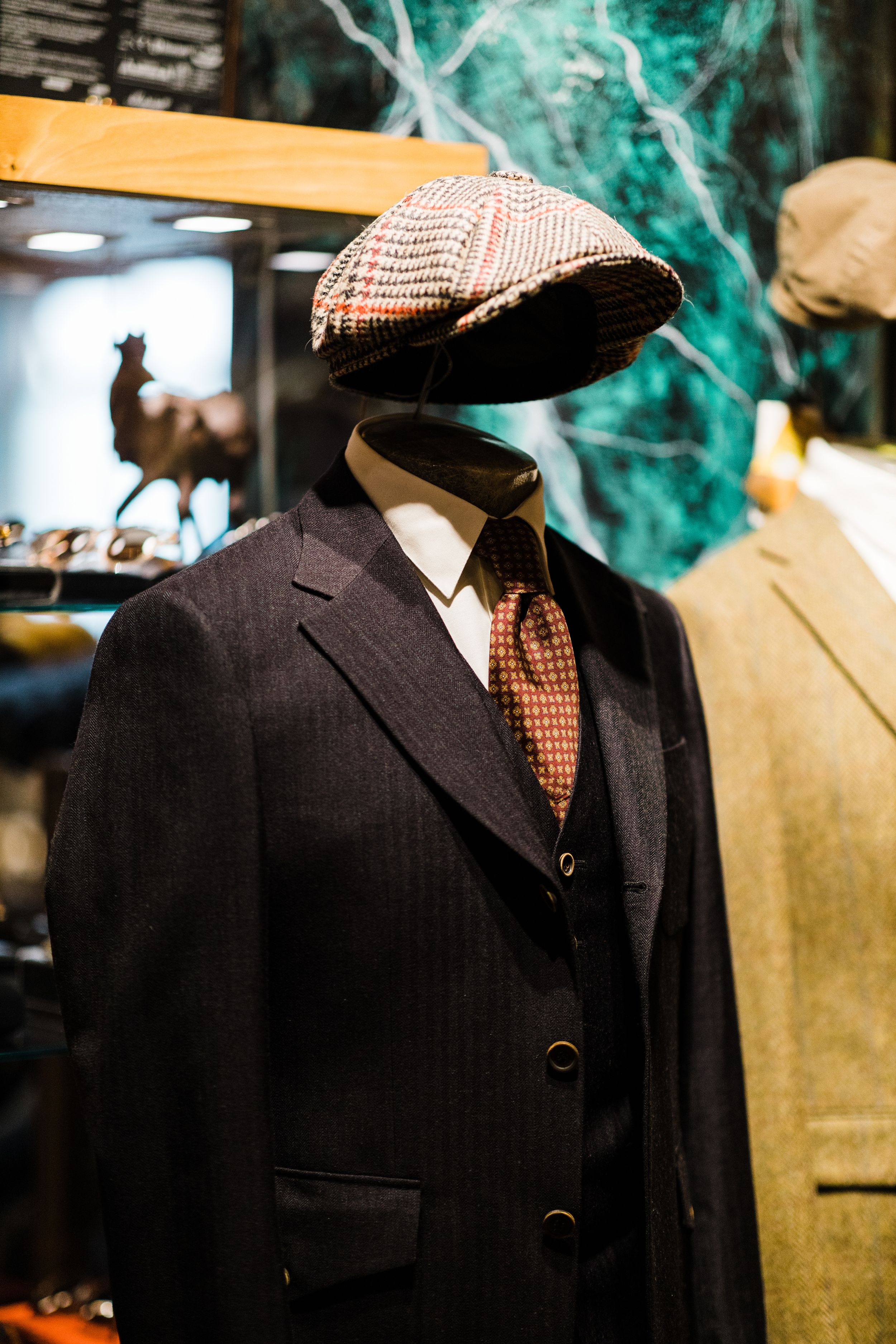 Vintage tweed flat cap and suit display on a mannequin in a menswear shop.