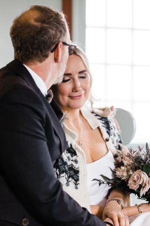 Intimate wedding moment captured by window with soft natural light.