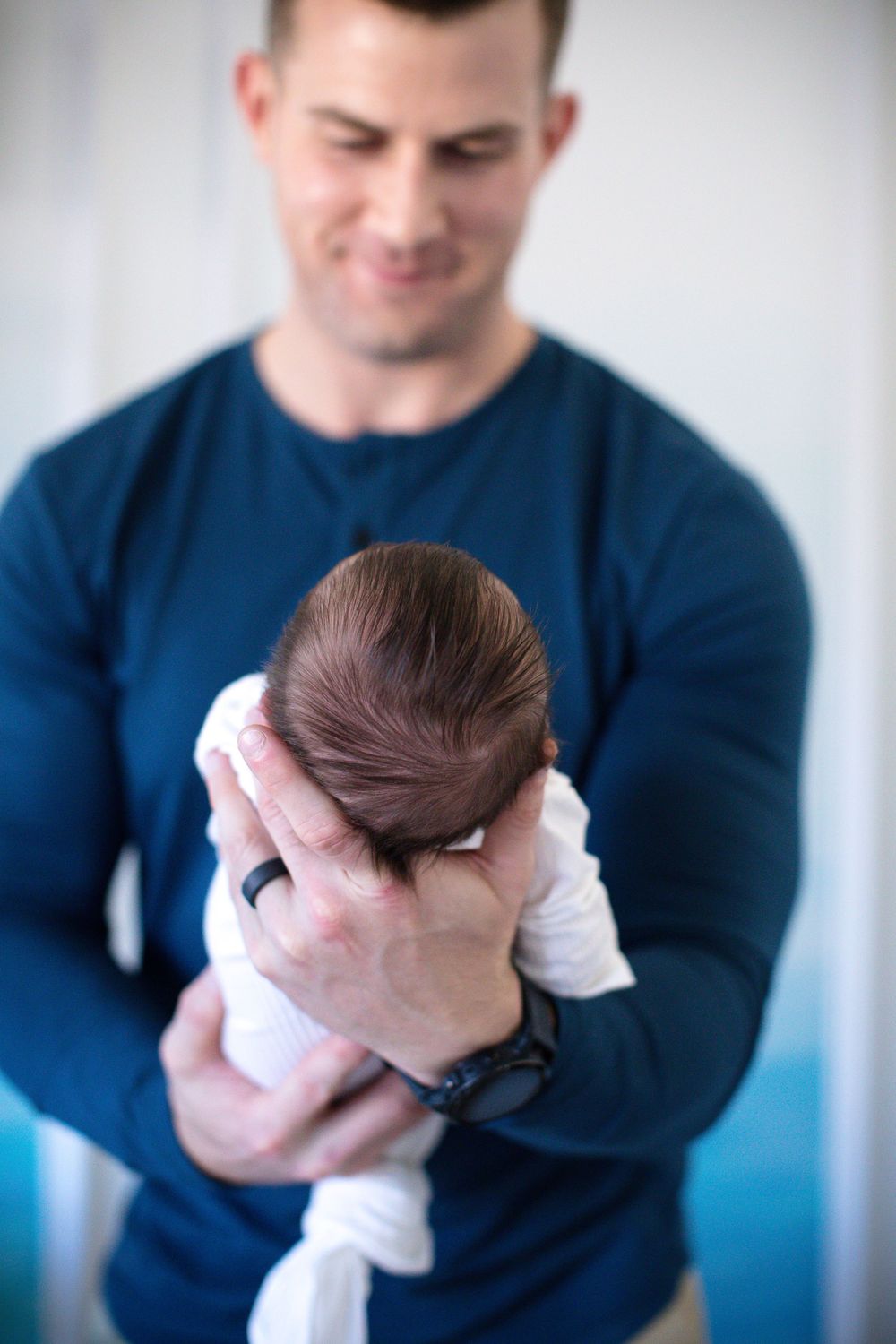 Parent in navy sweater tenderly holding their newborn baby against their chest in a loving embrace.