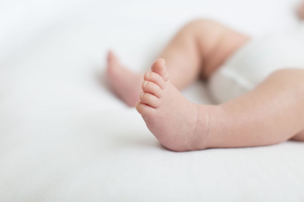 Close-up of tiny baby feet on soft white fabric.