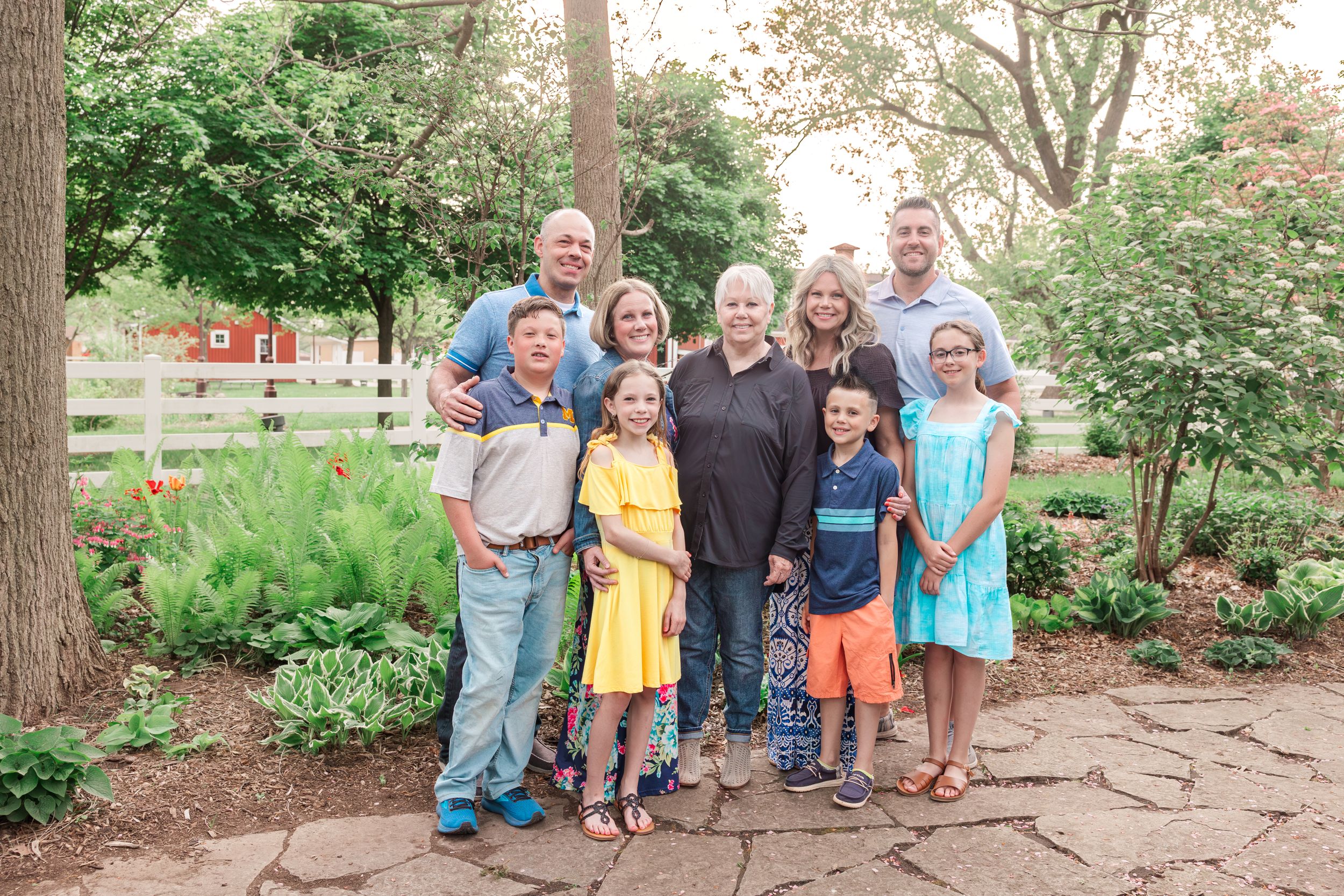 Extended family gathering outdoors in a garden setting with trees and landscaping.