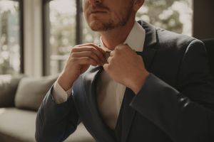 Close-up shot of someone adjusting their tie while wearing a formal suit.