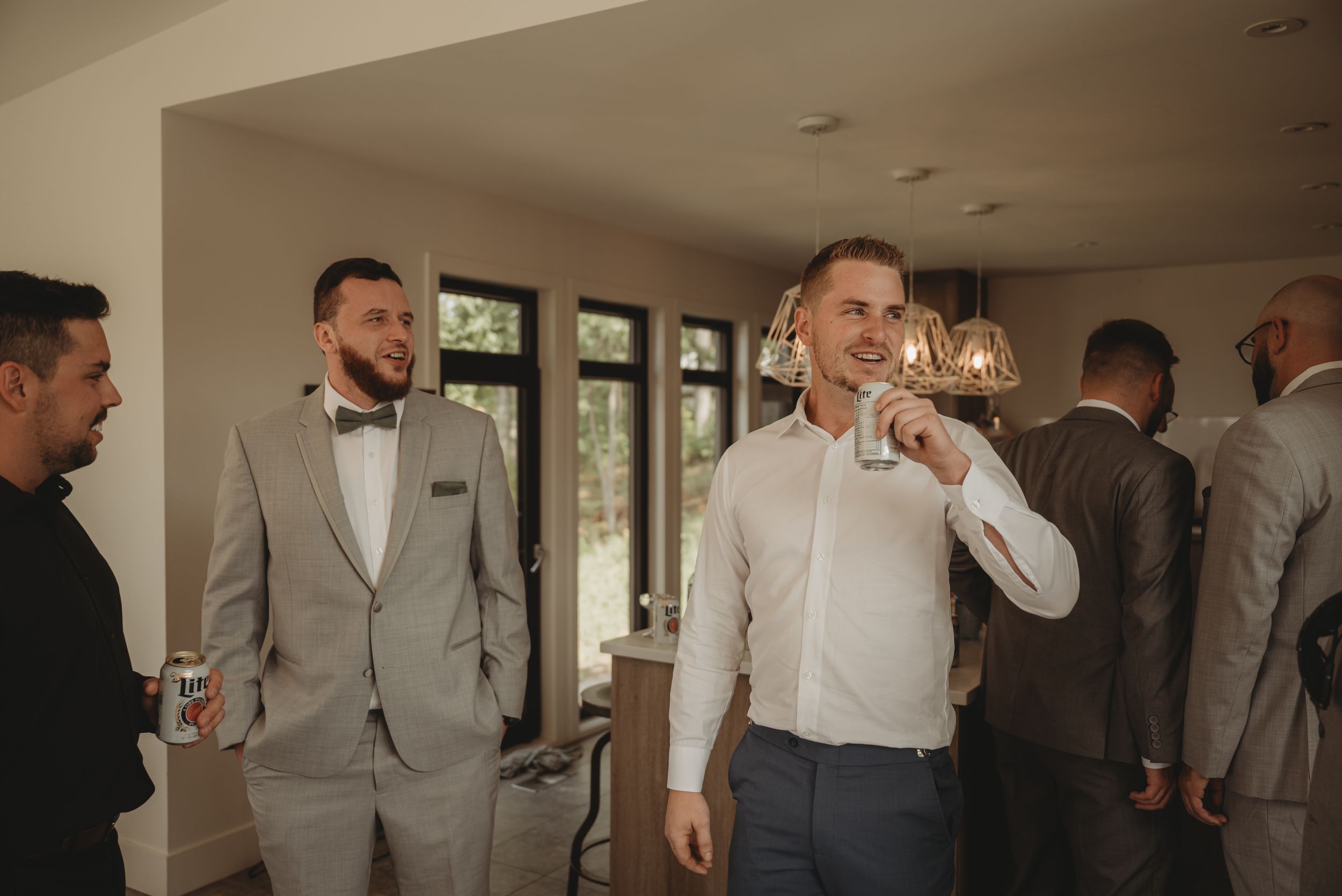 Groomsmen in formal attire gather before a wedding in a bright indoor space.