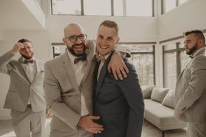 Candid moment of joy captured between groomsmen in formal wedding attire.