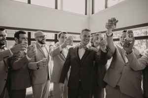 Wedding party raises glasses in celebration wearing matching gray suits.