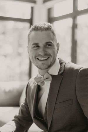 Classic black and white portrait of a groom in formal attire with bow tie.