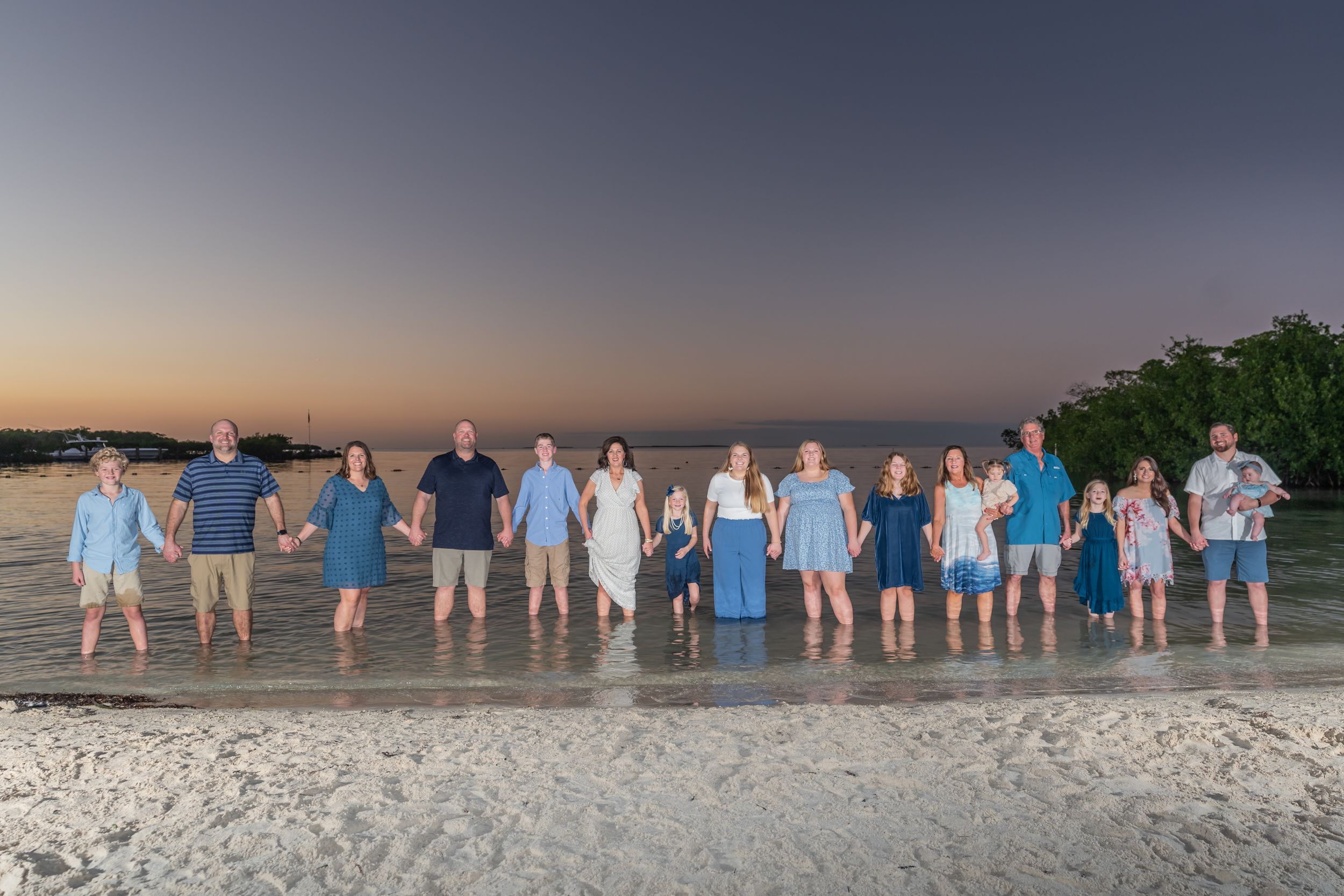 Line of people posing at dusk on a beach with fading light.