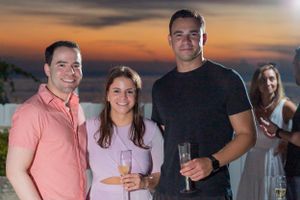 Sunset gathering with drinks and casual attire on a balcony or deck.