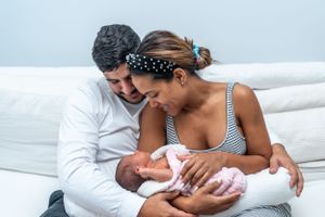 A tender moment shared with a newborn baby nestled on a white couch.