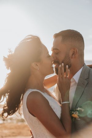 Intimate wedding portrait of a couple sharing a tender moment at sunset by the ocean.