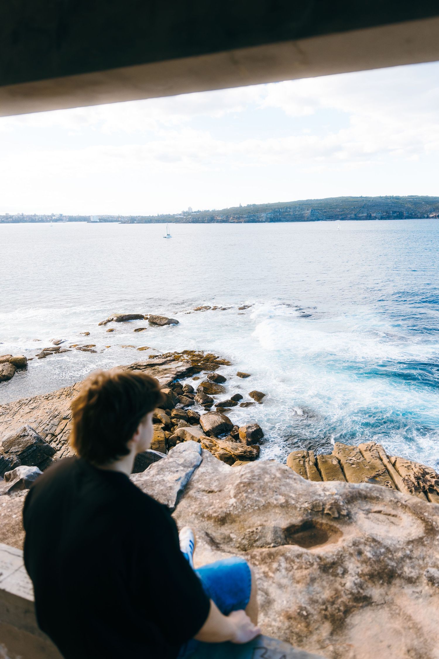 Man sitting on the edge of a cliff at Watsons Bay, Sydney. Crashing waves below.