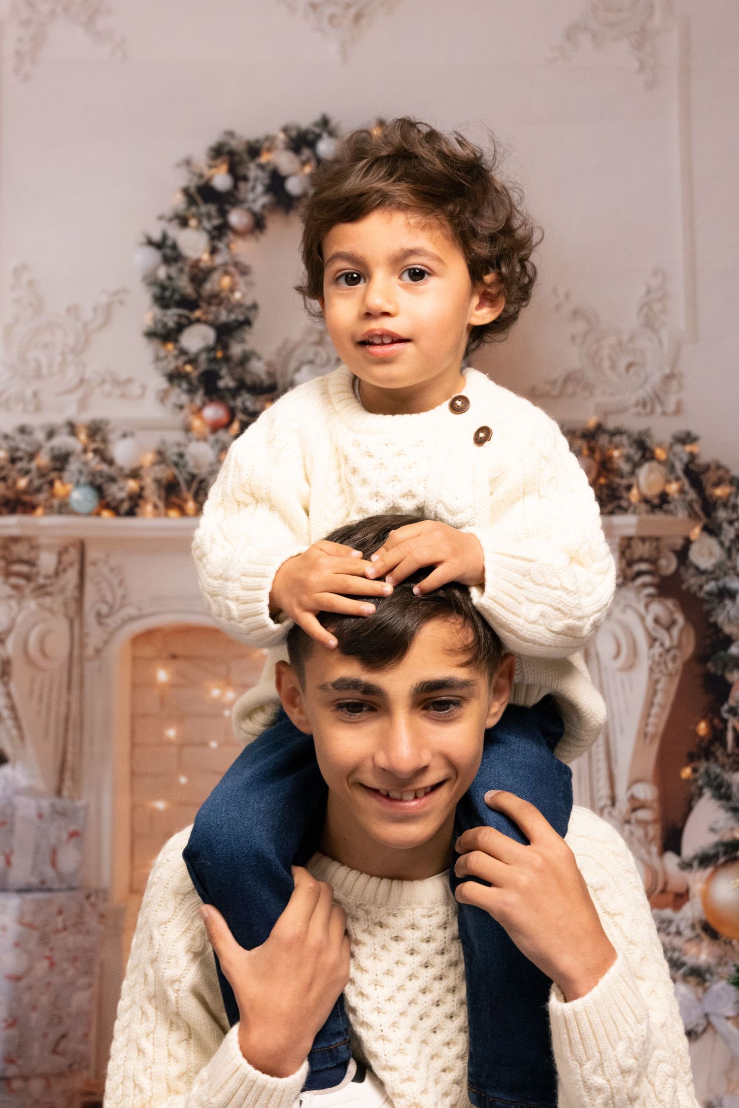 A festive holiday scene with white sweaters and Christmas decorations in the background.
