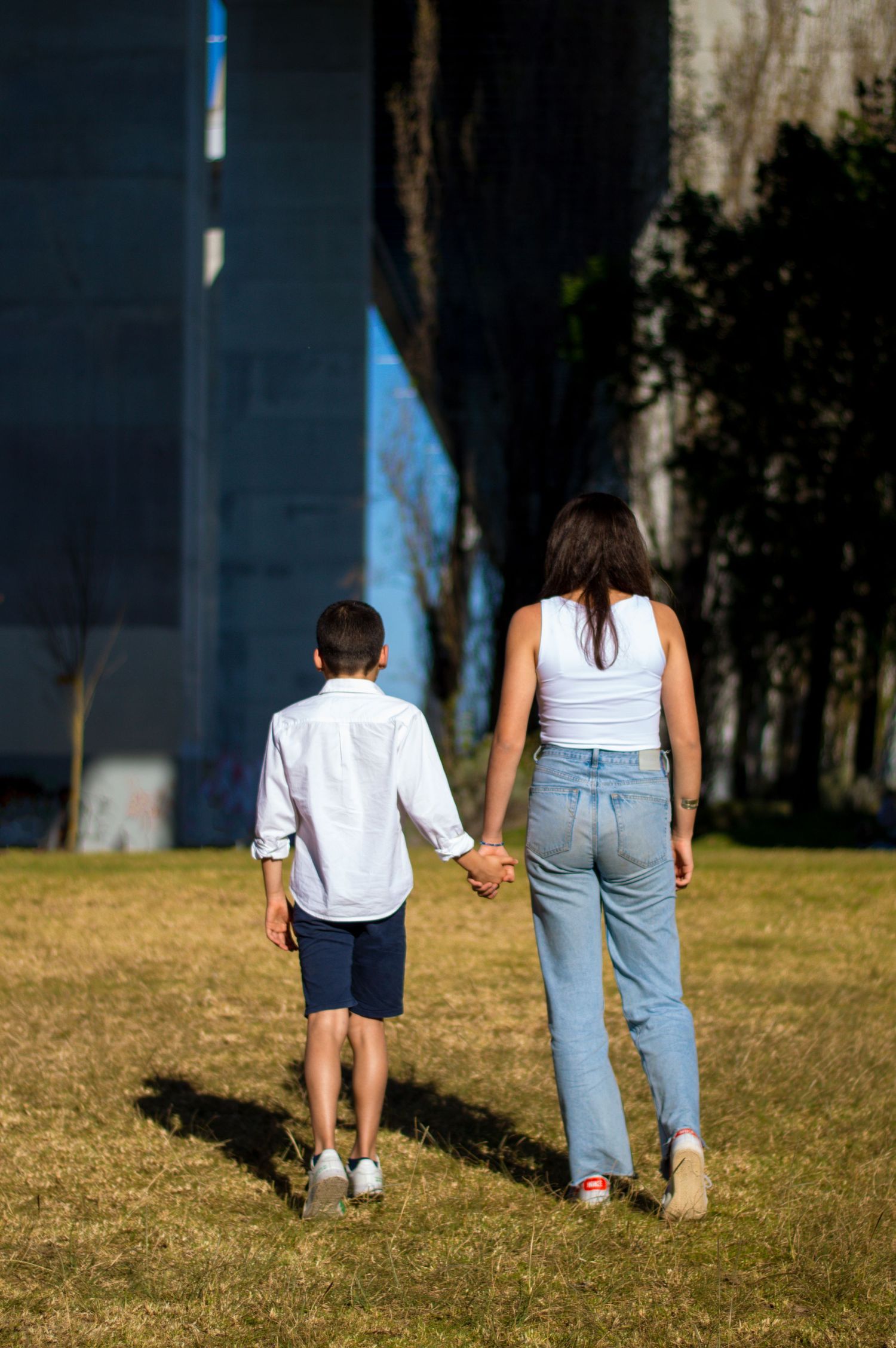 Two people walking together on grassy field on sunny day.