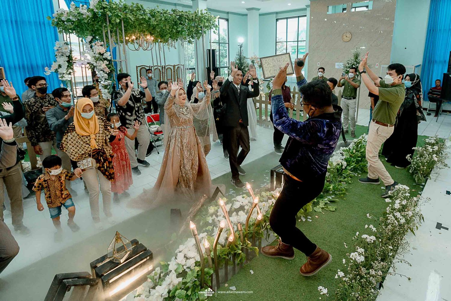 Wedding celebration with atmospheric fog effects and floral decorations in a modern blue-walled venue.
