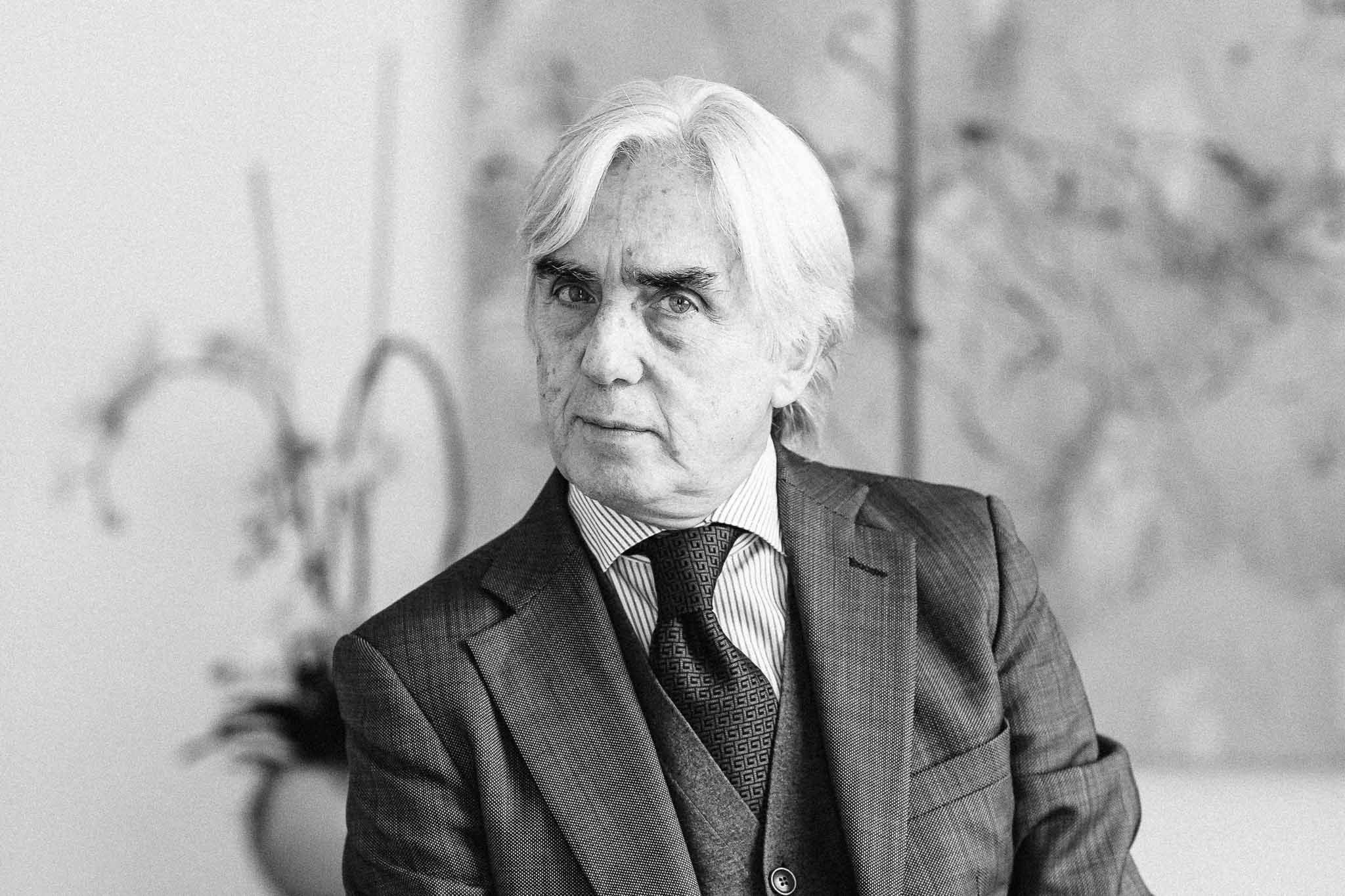 Black and white portrait of an elderly gentleman in a three-piece suit against a blurred background.