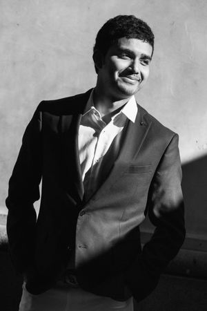 Professional headshot of person in suit jacket smiling against light background.