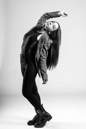 Contemporary dancer in black outfit performs expressive backbend pose against white background.