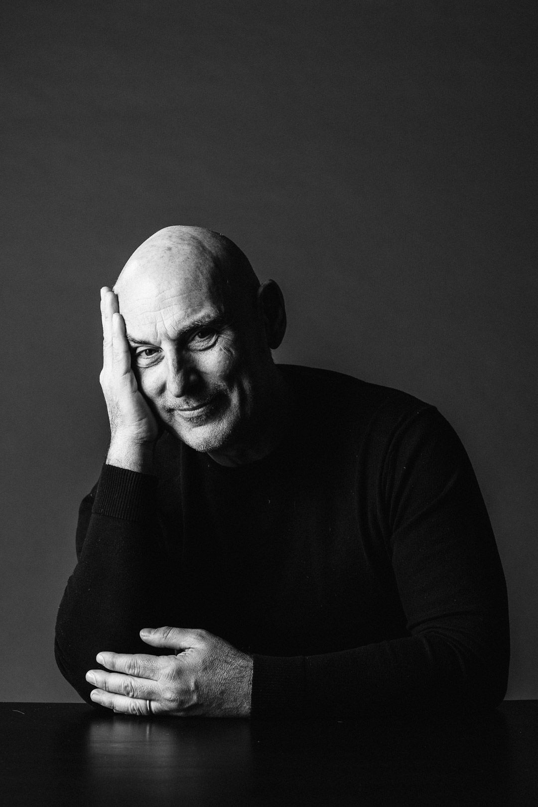 Black and white portrait of a person in dark sweater resting head on hand.