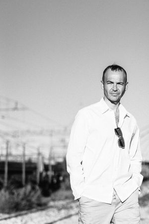 Black and white portrait of man in white shirt standing outdoors.