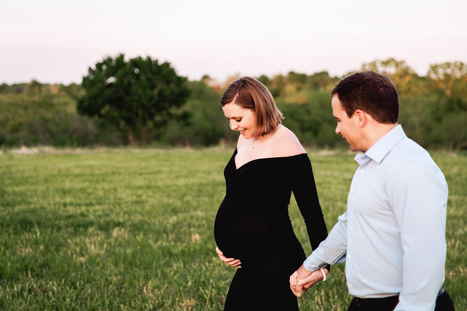 couple walking hand in hand in green field