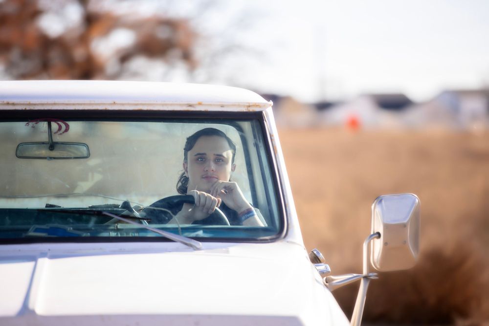 Vintage car driver looking through windshield on desert road.