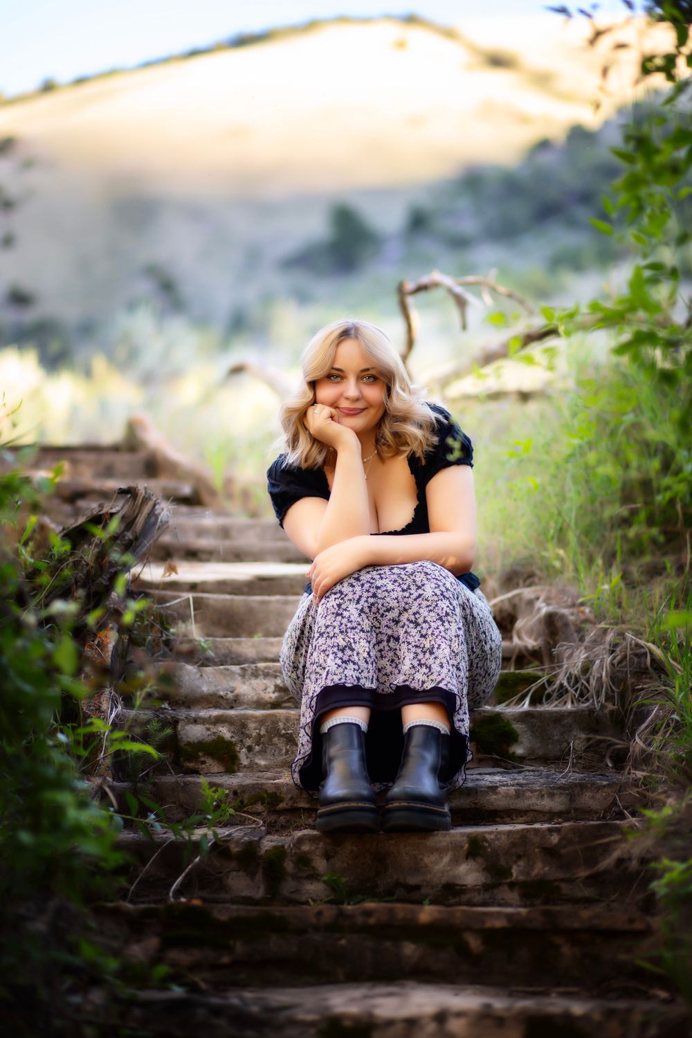 Portrait on rustic wooden steps surrounded by greenery at sunset.