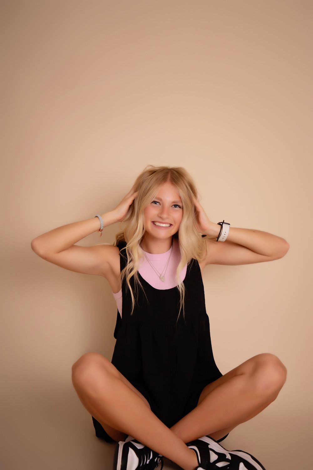 Studio portrait against beige background in casual black outfit.