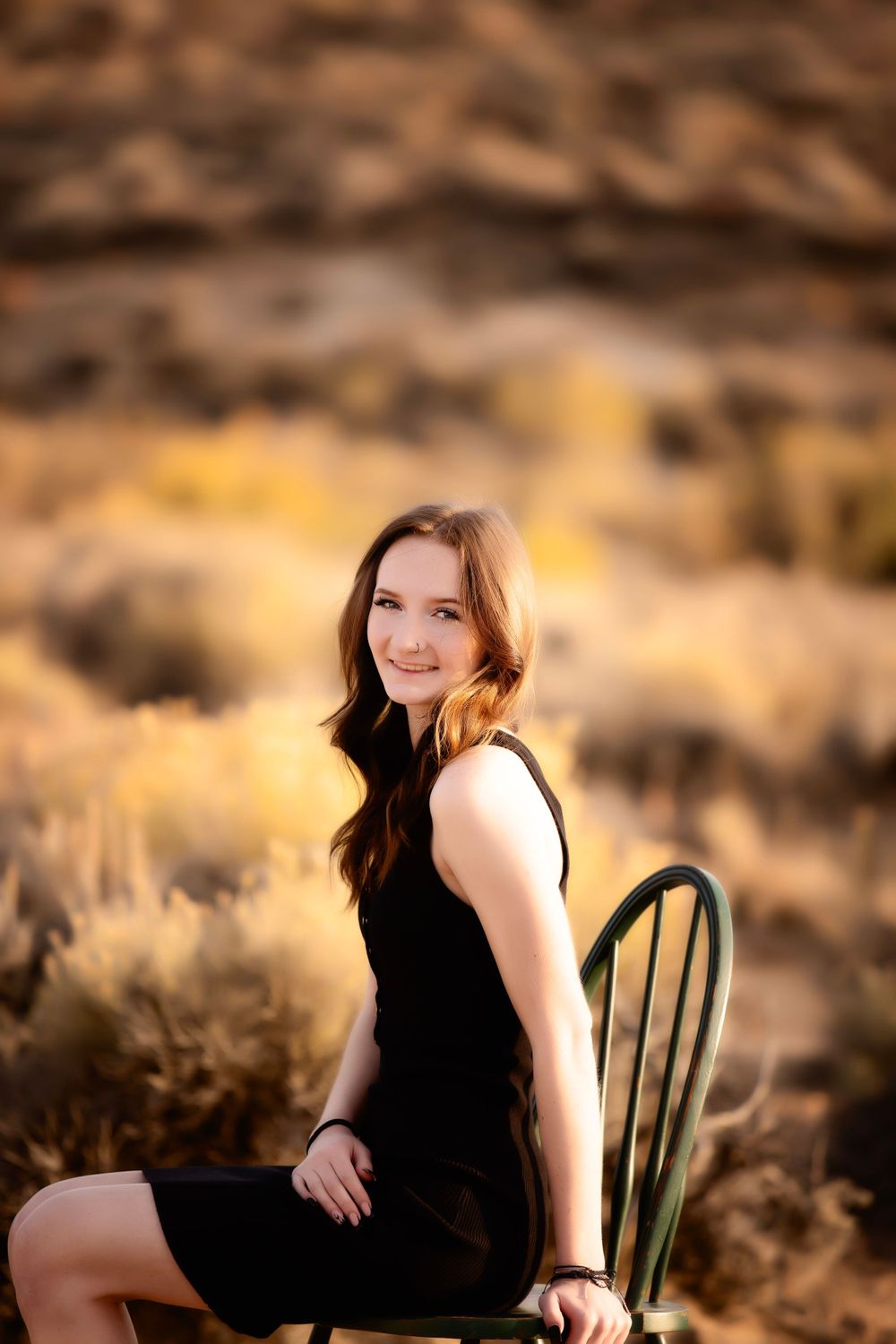 Portrait session in black dress against desert backdrop with golden lighting.