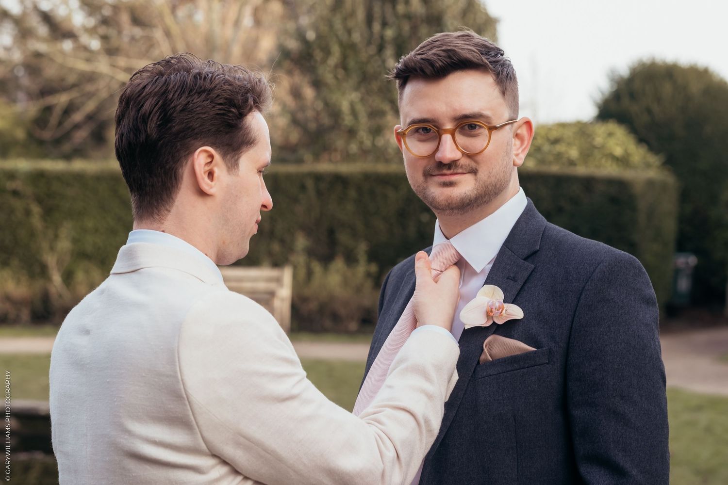 Newlywed groom fixing his spouse's tie at their gay wedding in Twickenham London