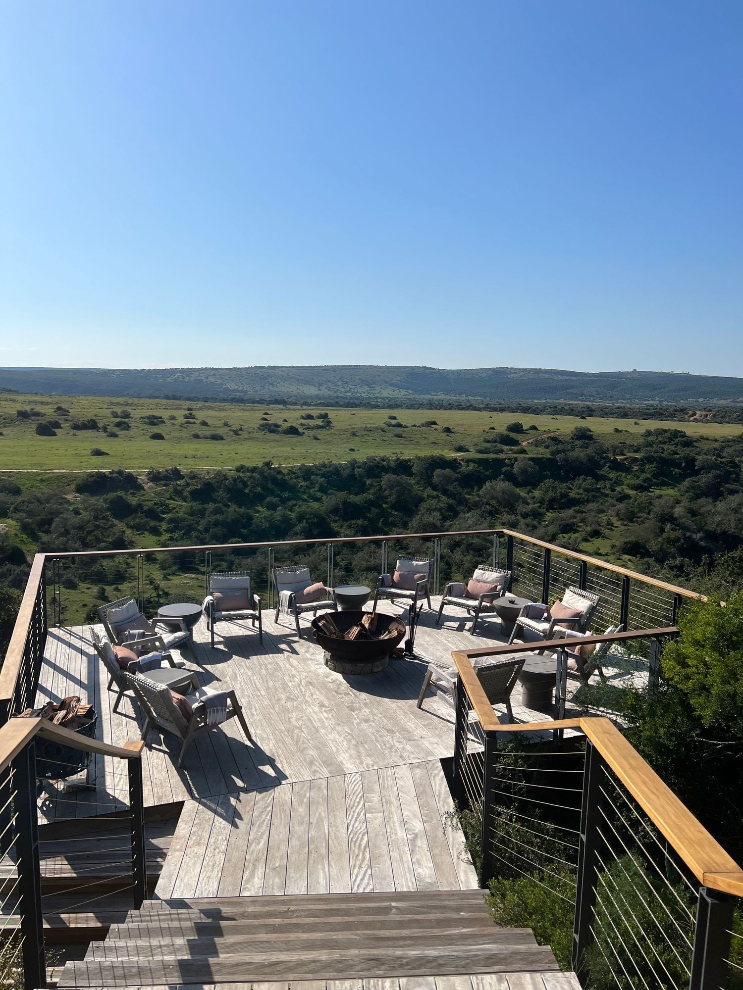 Panoramic view of rolling hills and countryside from elevated wooden deck stairs.