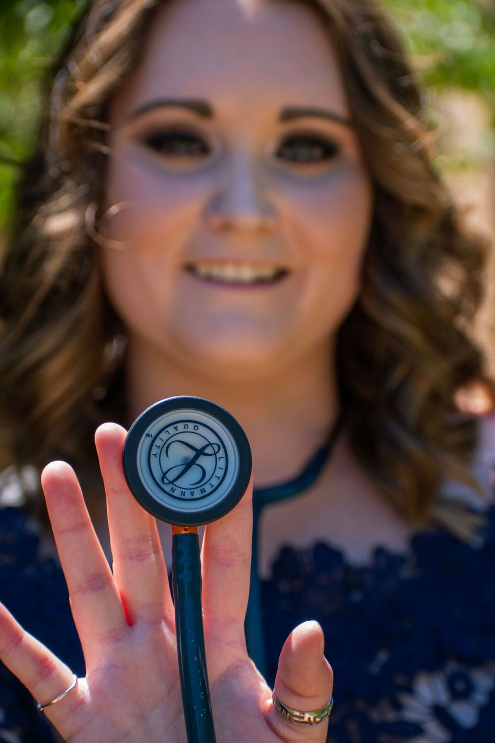 Close-up of graduate holding medical stethoscope during graduation photoshoot.