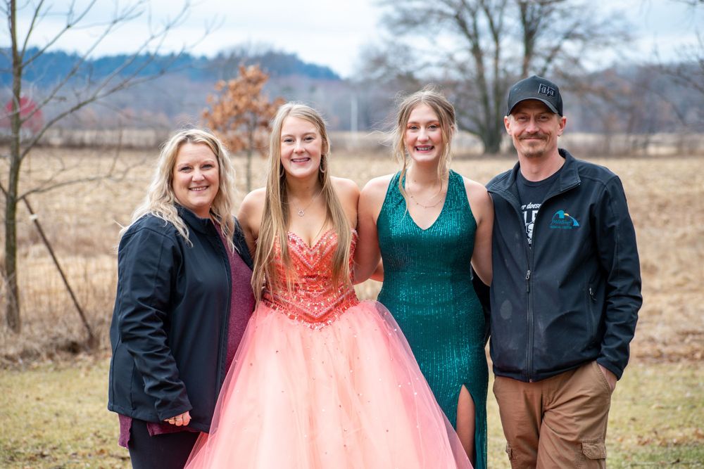 Outdoor group portrait session with people in formal attire against rural landscape.