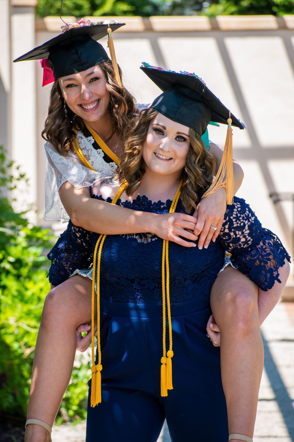 Graduates in matching navy gowns and gold tassels celebrate their achievement together.