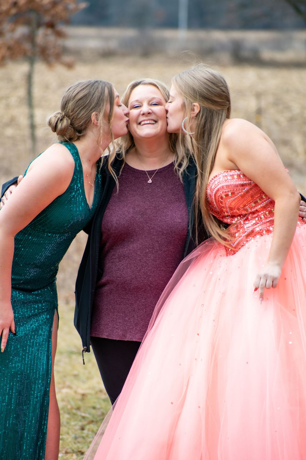 Candid moment of friends laughing together during formal photo session in nature.
