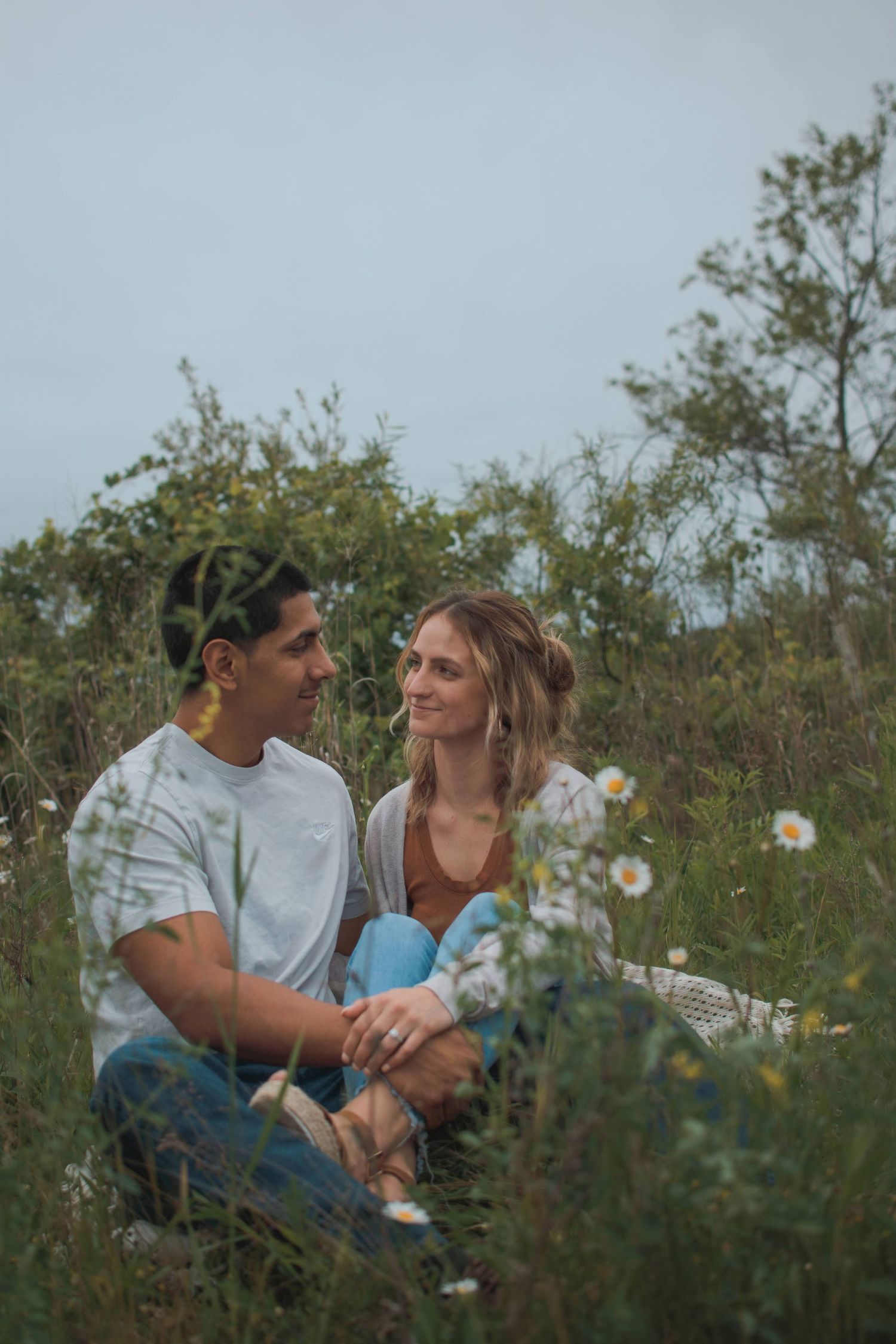 Romantic scene of a couple sitting in a field of flowers. Dreamy couple photography amidst blooming flowers,