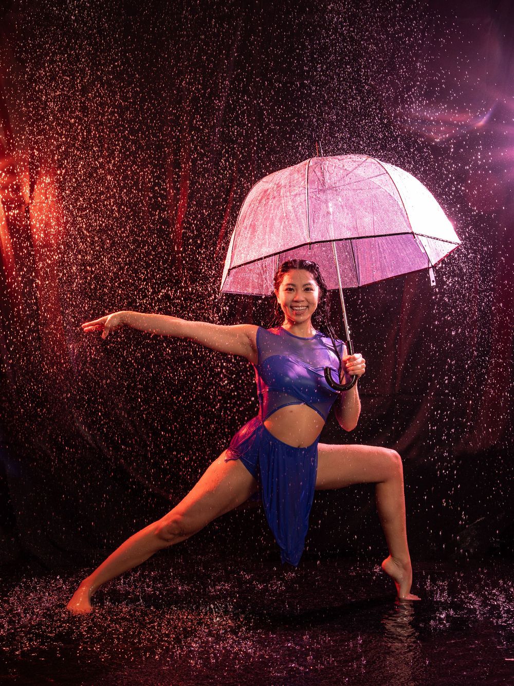 Female holding umbrella doing lunge pose in rain, by Brian Balloon Media