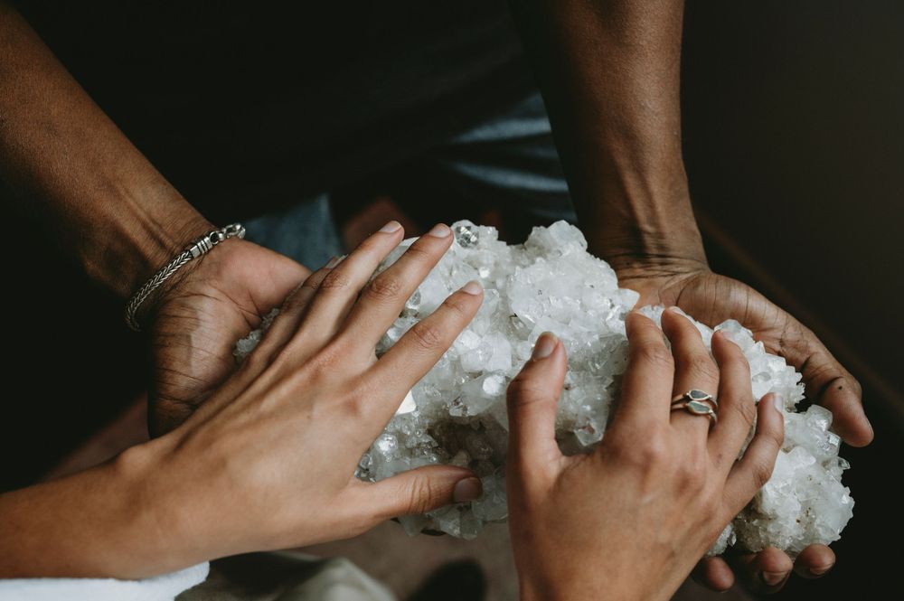 Close-up of hands holding white crystal or mineral specimens.