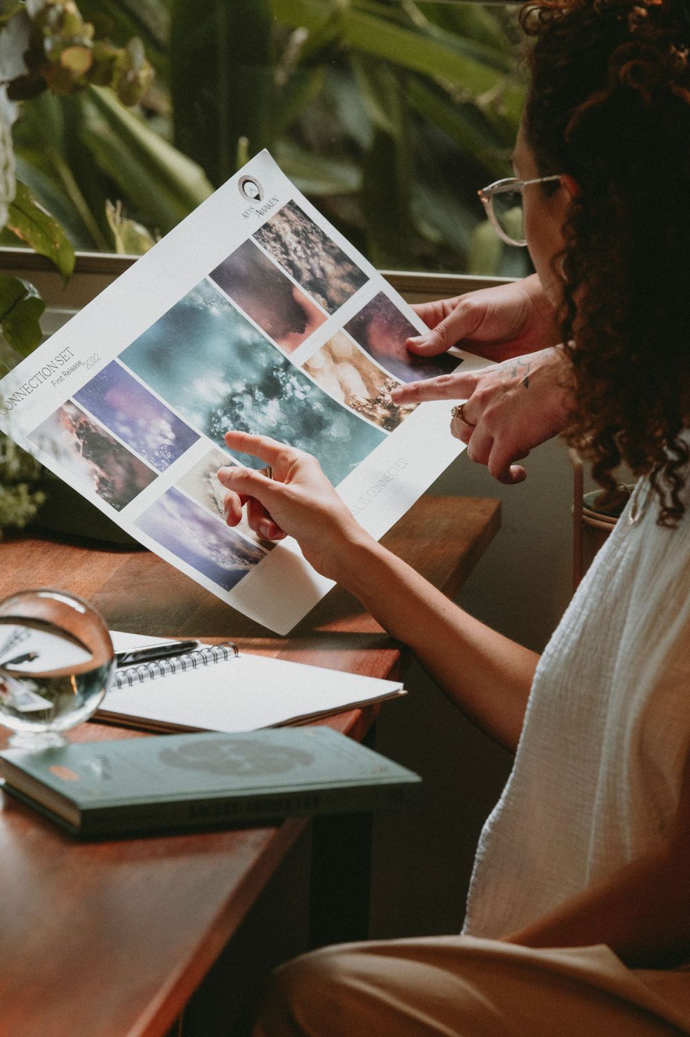 Hands holding and looking through printed photographs on wooden table.