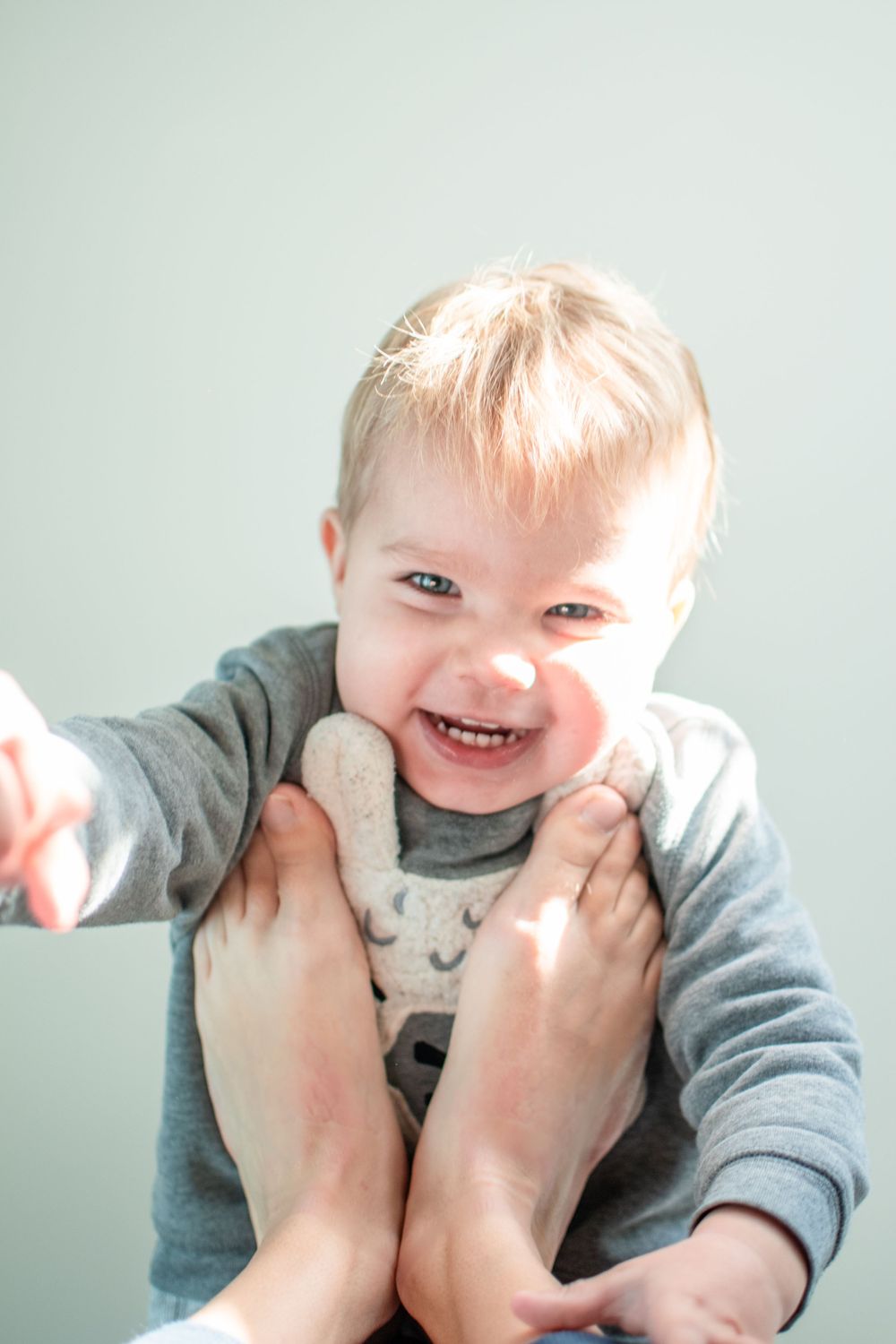 Joyful moment during playtime with grey sweatshirt and gentle hands.