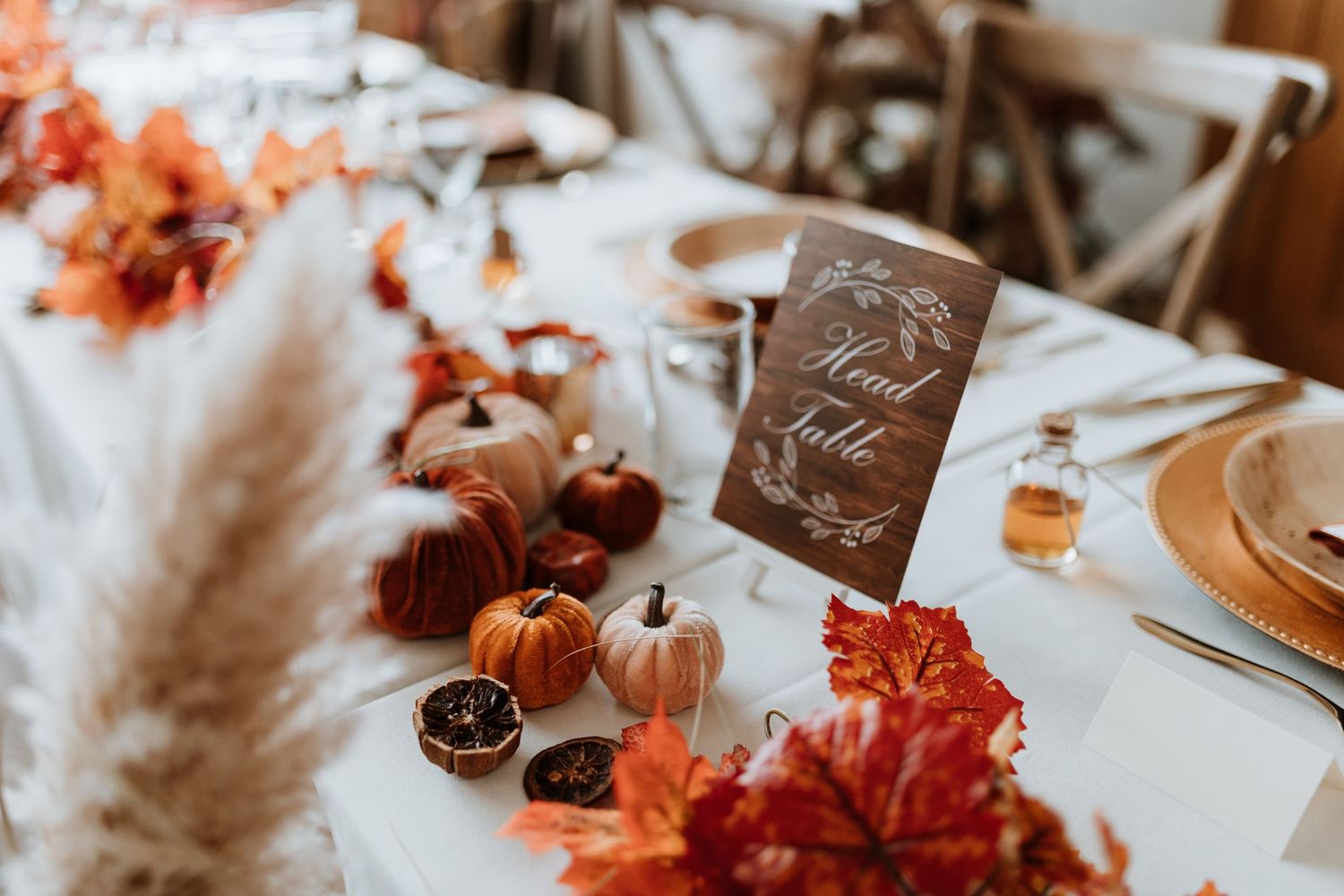 Autumn rustic wedding table scape using maple leaves, dried oranges, pinecones and pumpkins.