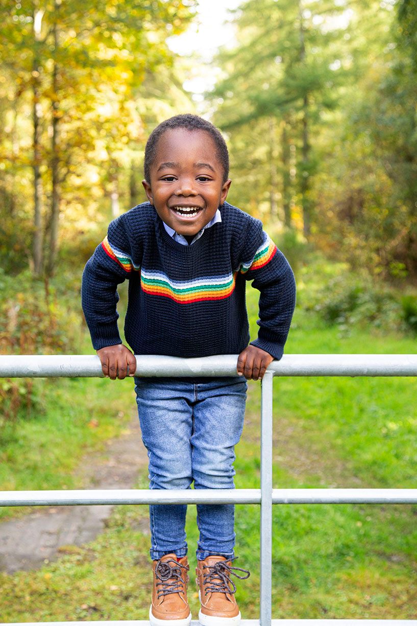 Little boy playing on a metal gate.