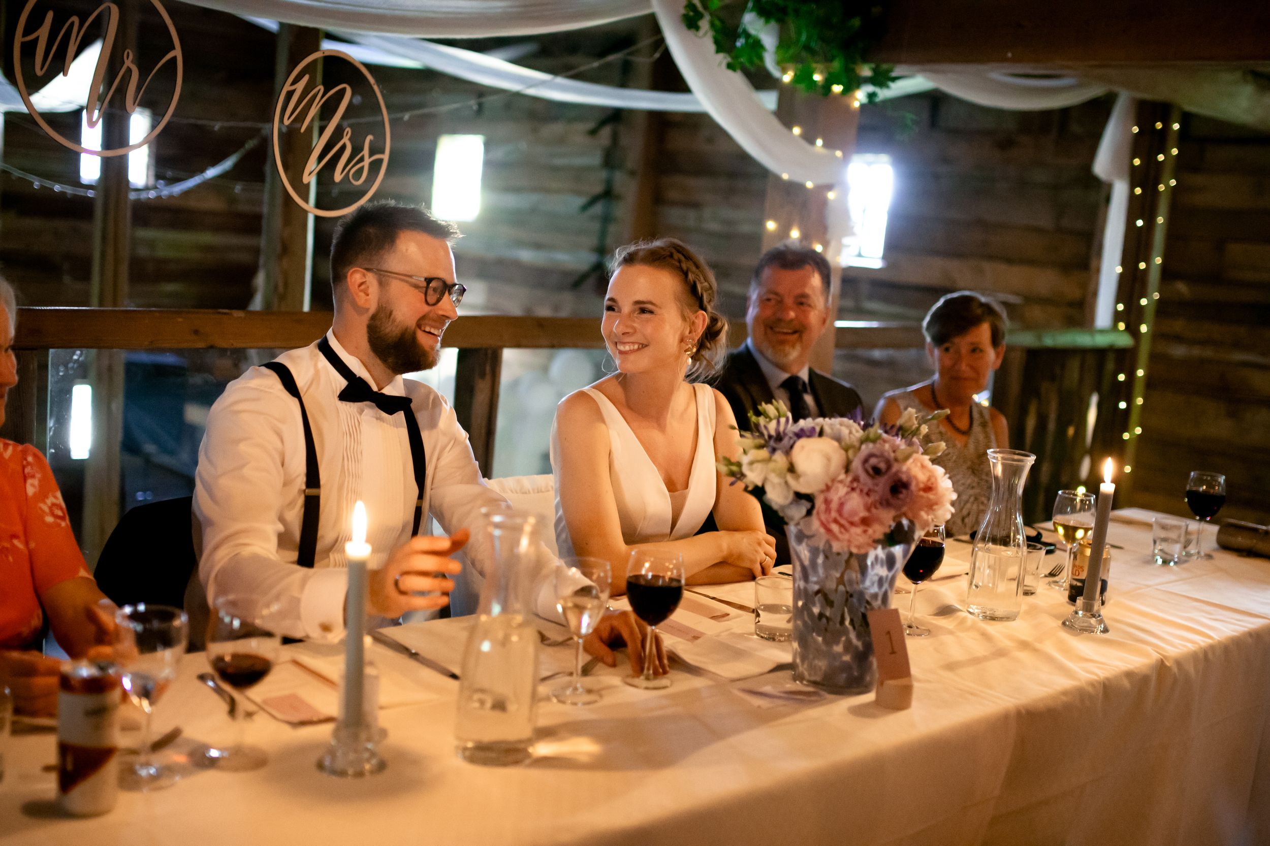 Intimate wedding reception moment at decorated head table with ambient lighting.