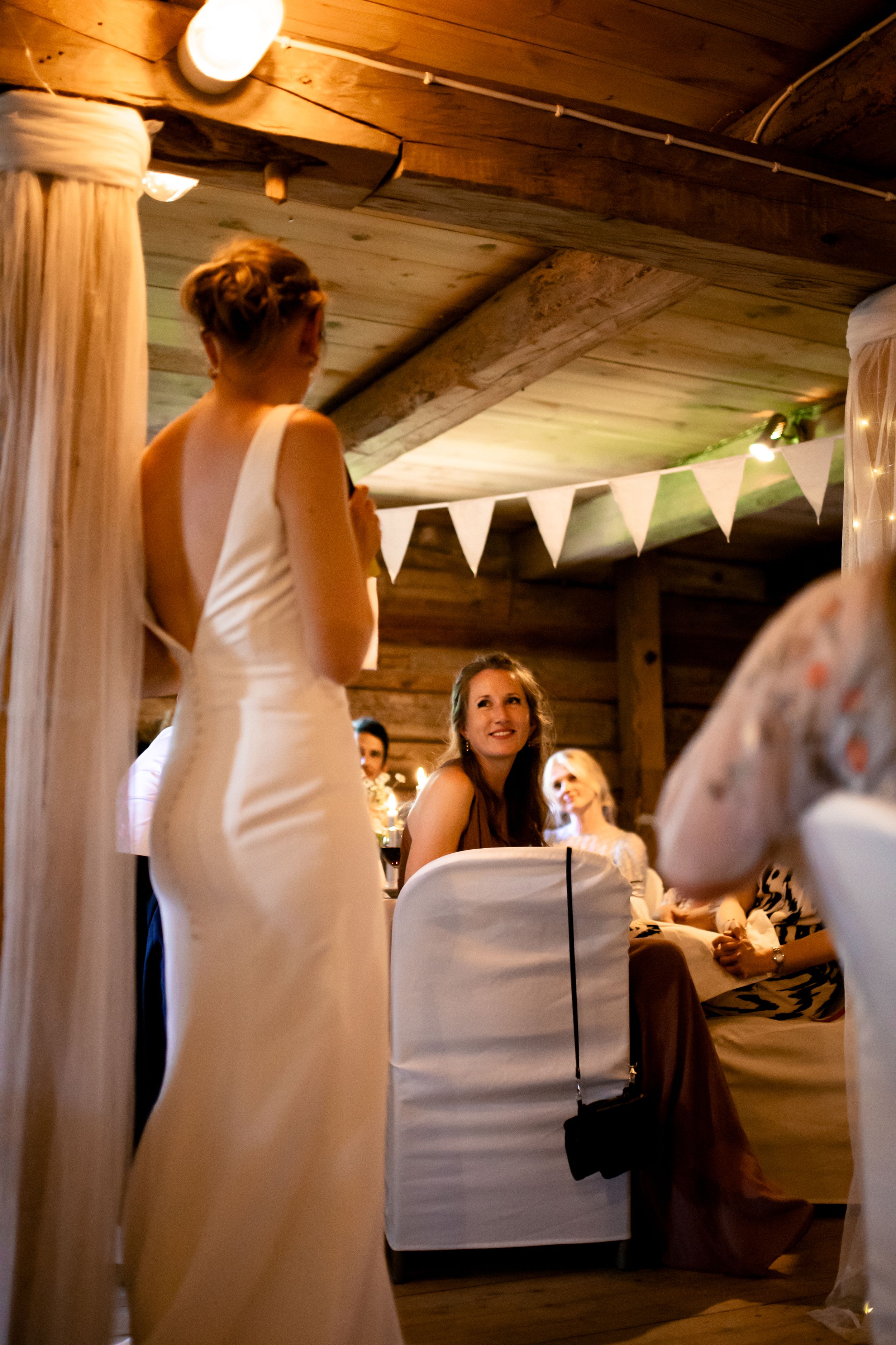 Elegant indoor wedding celebration with white decorative bunting and wooden beam ceiling.