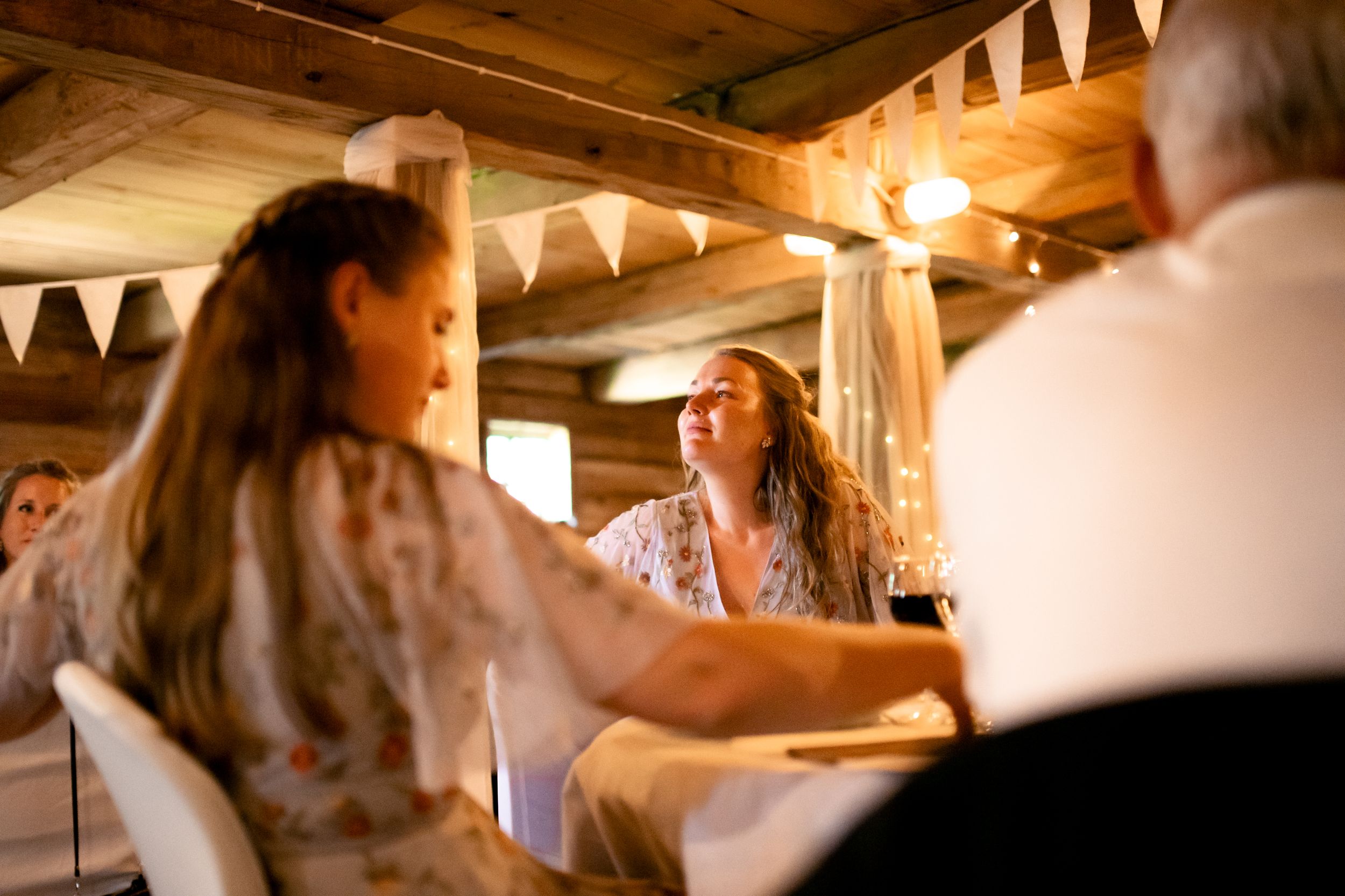 Wedding guests enjoying a lively moment at a rustic indoor reception venue.