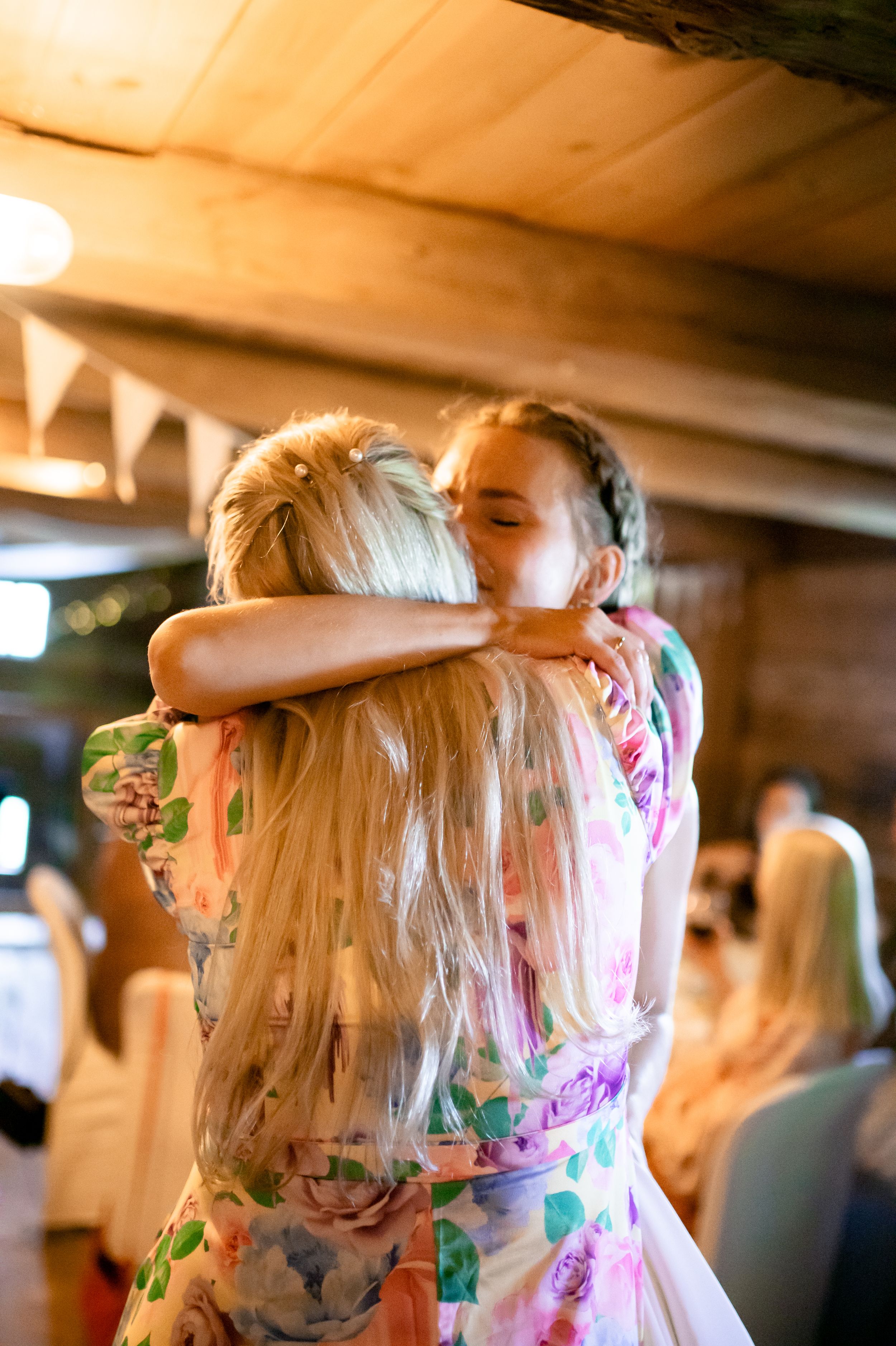 Two wedding guests sharing an emotional embrace at a festive reception.